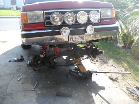 1990 Ford Bronco - Front suspension work on a 1990 Ford Bronco, with the vehicle raised and parts disassembled.