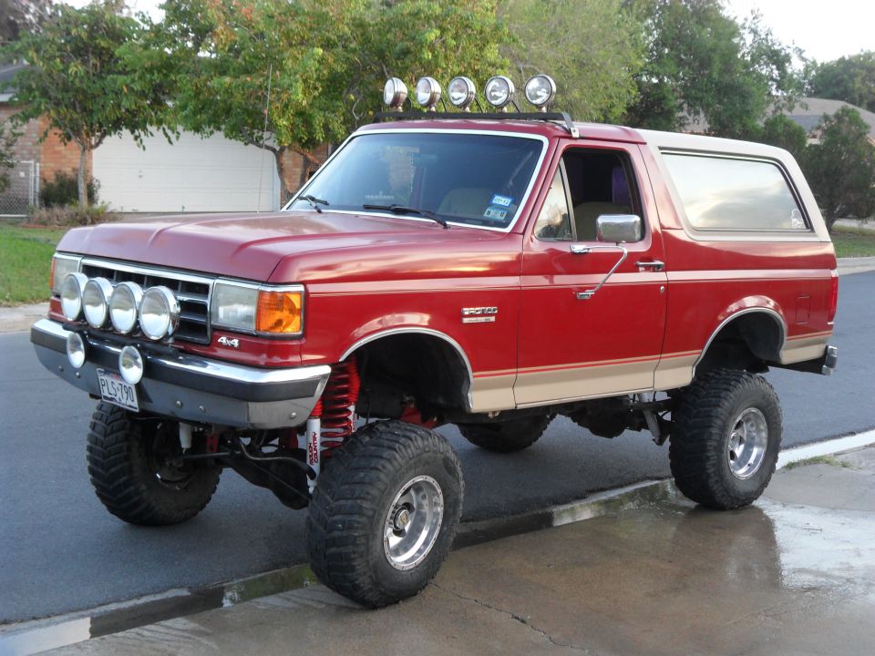 1990 Ford Bronco, red with tan trim, lifted suspension, roof-mounted and bumper-mounted lights