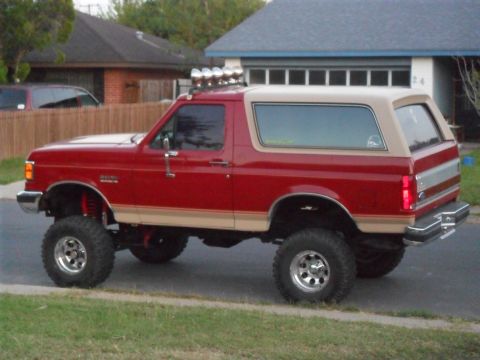 1990 Ford Bronco - This lifted Ford Bronco has a two-tone paint scheme with a tan top and tan lower body trim.
