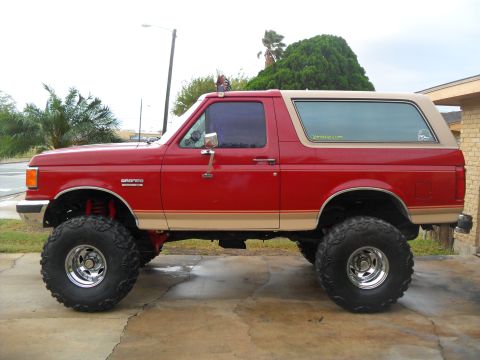 1990 Ford Bronco - This lifted 1990 Ford Bronco is shown in profile, its distinctive two-tone paint scheme and off-road tires.