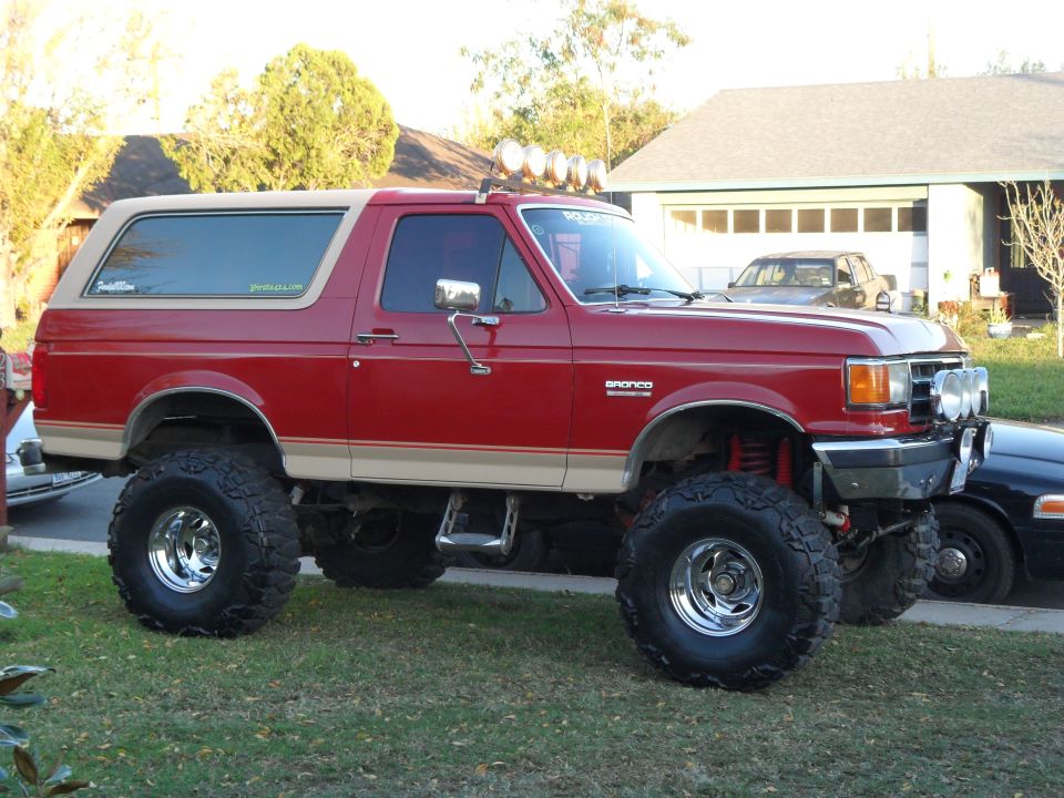 Red 1990 Ford Bronco with tan trim and lifted suspension
