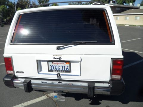 1994 Jeep Cherokee - Rear view of a white 1994 Jeep Cherokee, showing the tailgate, taillights, and California license plate.