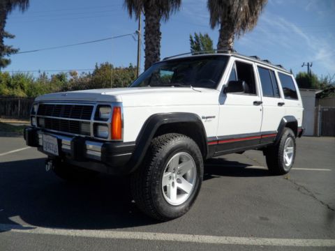 1994 Jeep Cherokee - This white 1994 Jeep Cherokee is shown from the front three-quarter angle, highlighting its distinctive body style and red accent stripe.