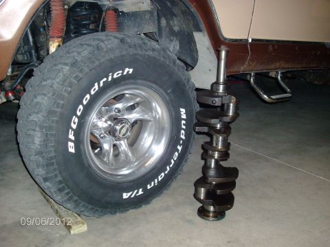 1979 Ford F-150 - A crankshaft is shown next to the tire of a 1979 Ford F-150, likely during an engine teardown.