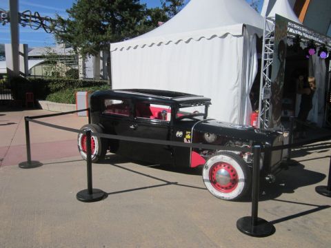 1991 Ford LTD Crown Victoria - A custom hot rod is displayed outdoors near a white tent and stage setup.
