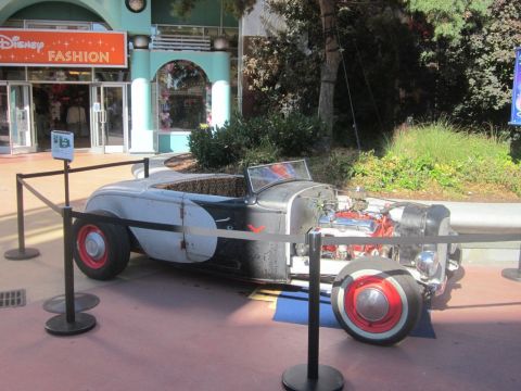 1991 Ford LTD Crown Victoria - A custom hot rod with its engine visible is displayed in front of a Disney Fashion store.