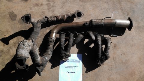 1995 Ford Probe - Two exhaust manifold assemblies and a section of exhaust pipe are shown on a concrete surface.