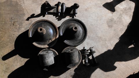 1995 Ford Probe - Various used suspension parts are arranged on a concrete floor, casting long shadows.