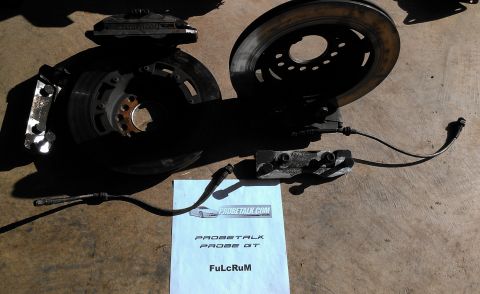 1995 Ford Probe - Brake caliper and rotor assembly with a document from Probetalk.com visible.