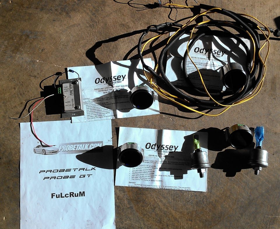 Odyssey Series II boost, fuel pressure and EGT gauges with wiring harnesses and instruction sheets on concrete