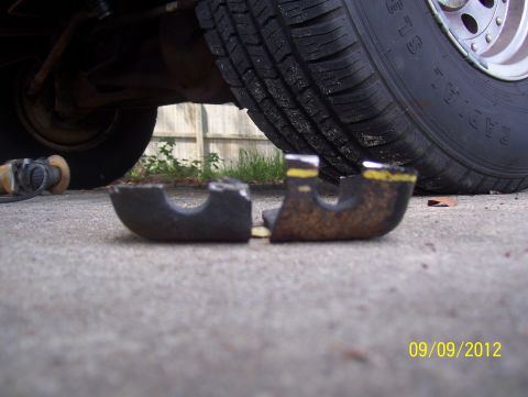 1990 Ford Bronco - A broken metal part with yellow markings lies on concrete near a vehicle tire, with a date stamp of 09/09/2012.