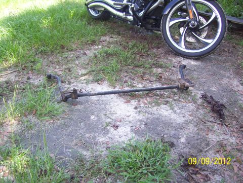 1990 Ford Bronco - A motorcycle is parked next to a detached automotive suspension component on the ground.