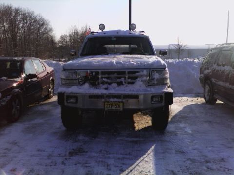 1994 Ford C-350 (Centurion Conversions) - A snow-covered truck is parked outside in a lot with other vehicles.
