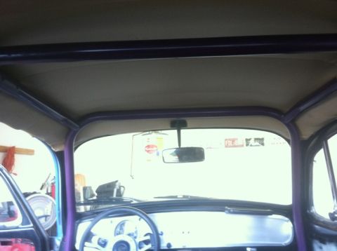 1970 Volkswagen Beetle - The interior of a custom vehicle features a prominent purple roll cage and a beige headliner, viewed from the driver's seat.