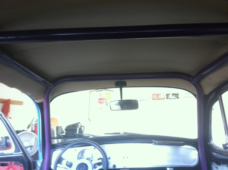 Interior view of a custom car with a purple roll cage and beige headliner