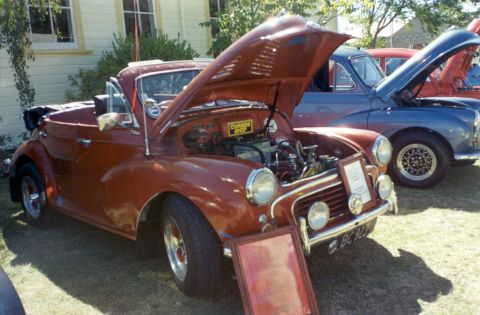1969 MINI Cooper - A classic Morris Minor convertible is displayed with its engine exposed, alongside other vintage vehicles.