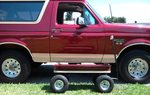 1994 Ford Bronco - Side profile of a two-tone burgundy-and-tan Ford Bronco with a "BRONCO 5.8" fender badge, chrome mirror, whip antenna and argent styled ste…
