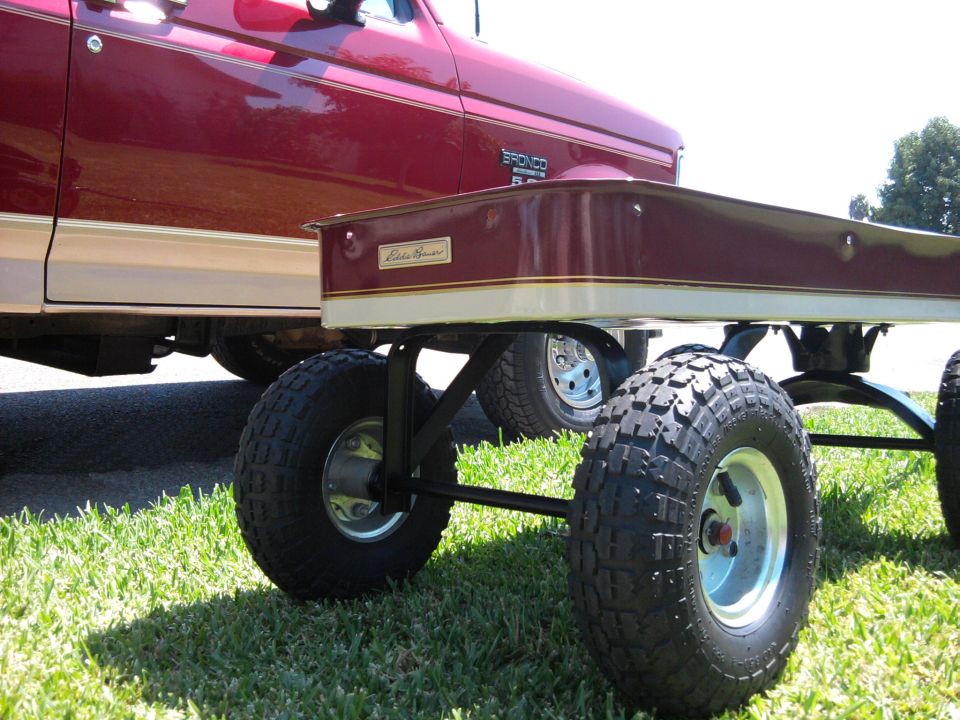 Custom Eddie Bauer wagon on knobby tires in grass with matching red and tan Ford Bronco behind