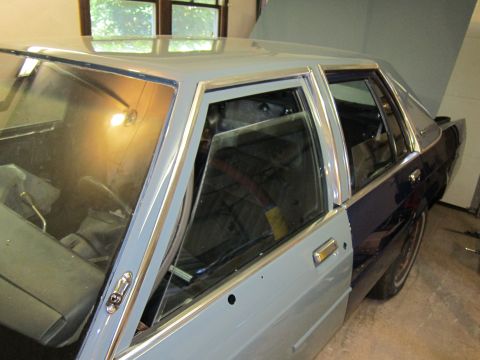 1991 Ford LTD Crown Victoria - A 1990 Ford Crown Victoria sedan is shown with a primer gray front fender and dark blue rear body panels.