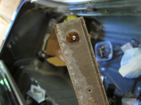 1991 Ford LTD Crown Victoria - A close-up shot focuses on a corroded metal strip, likely part of a car's interior trim, with a visible screw hole.