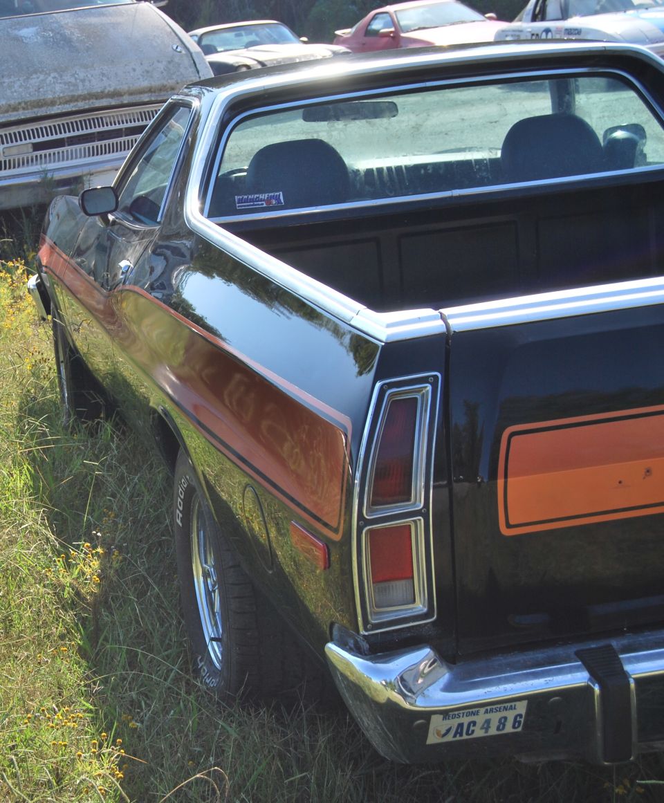 Black Ford Ranchero with orange stripe, parked next to other vehicles