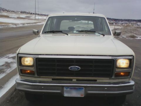 1986 Ford Bronco - Front view of a white Ford Bronco with a dark grille and chrome bumper.