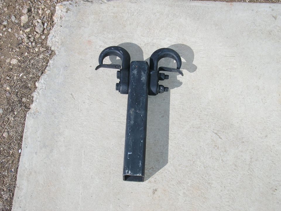 Black tow hitch receiver with two hooks, sitting on concrete