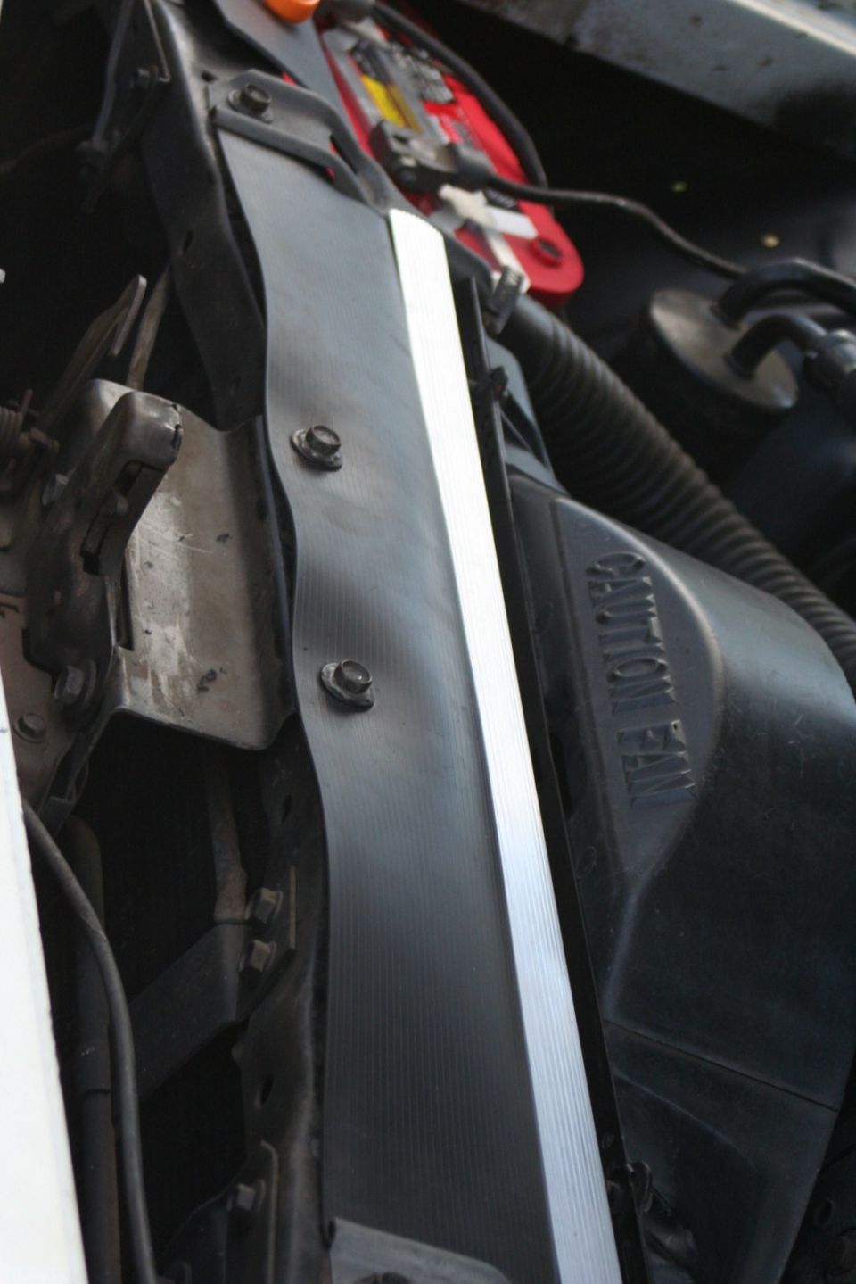 Close-up of a car's radiator fan shroud with 'CAUTION FAN' text visible
