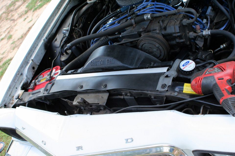 White 1976 Ford Ranchero engine bay with a red drill on the radiator