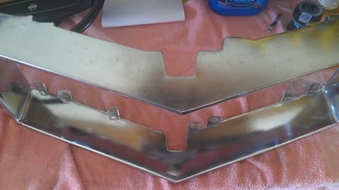 1973 Chevrolet Camaro - A chrome grille part is shown resting on a red cloth, with a bottle of cleaner and tape in the background.