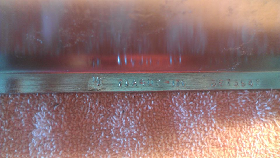 Close-up of a metal part with stamped numbers and letters, possibly a VIN or part number