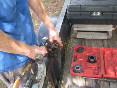 1994 Ford Bronco - A person is working on a vehicle part with an angle grinder, with a tool case nearby.