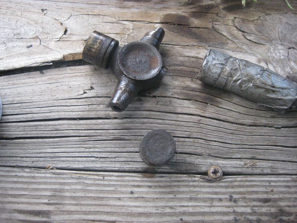Close-up of a universal joint and a piece of a driveshaft on a wooden surface