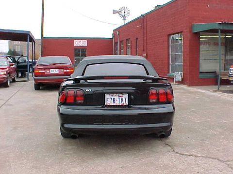 1995 Ford Mustang - Rear view of a black convertible with a license plate F78-TKT parked in a lot.