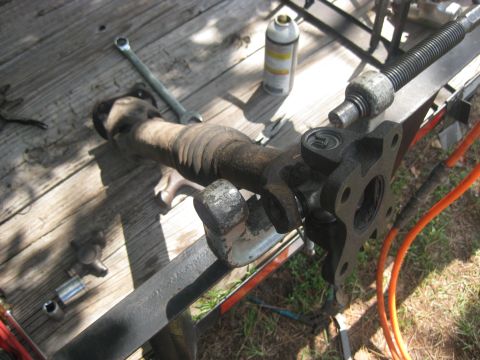 1994 Ford Bronco - A driveshaft component rests on a wooden surface, surrounded by tools and a can of spray.