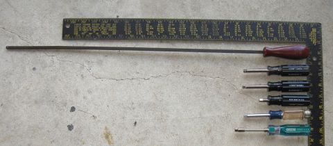 2000 Ford Crown Victoria - A collection of tools, including a long rod, ruler, and screwdrivers, are laid out on a concrete surface.