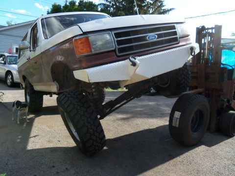 1989 Ford Bronco - This lifted Ford Bronco has a custom front bumper and is being supported by a forklift.
