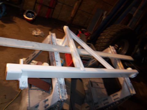 1989 Ford Bronco - A white metal frame, possibly a bumper or structural component, is mounted on sawhorses in a workshop setting.