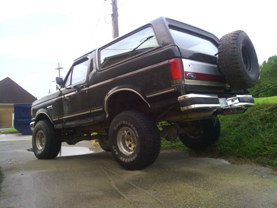 Dark brown Ford Bronco with a spare tire mounted on the rear, viewed from the rear quarter