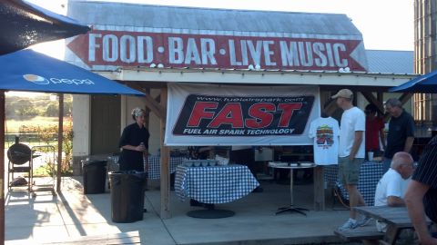 2007 Ford Mustang - Outdoor event with food, bar, and live music advertised on a building sign.
