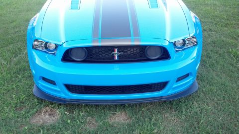 2007 Ford Mustang - A bright blue Ford Mustang is parked on a grassy lawn, showing its front grille and headlights.