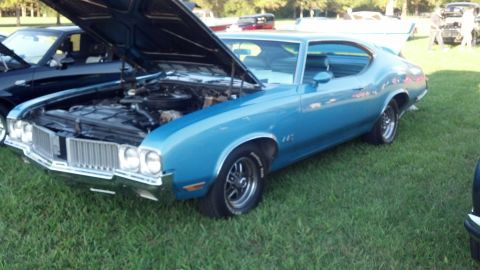 2007 Ford Mustang - A blue coupe with its hood open is parked on grass next to another vehicle.