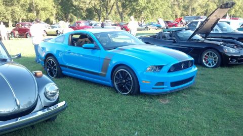 2007 Ford Mustang - Blue Ford Mustang with racing stripes at an outdoor car show.