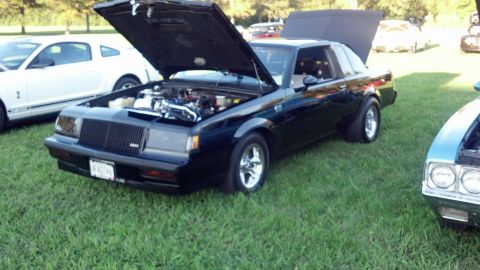 2007 Ford Mustang - A black Buick Regal Grand National is displayed with its hood open, parked on a grassy field next to other vehicles.