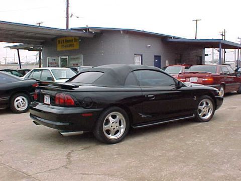 1995 Ford Mustang - This black 1995 Ford Mustang convertible is seen from a three-quarter front view, parked in front of a dealership.