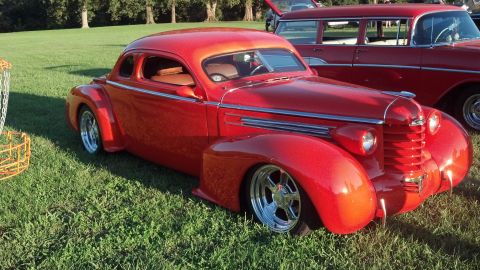 2007 Ford Mustang - A red hot rod coupe sits on a grassy field, with another red vehicle behind it.