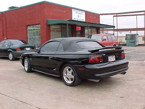 1995 Ford Mustang - Black 1995 Ford Mustang Cobra convertible seen from the rear, parked in a lot.