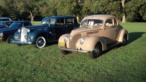 2007 Ford Mustang - A tan coupe from 1939 is parked on a grassy field next to other vintage vehicles.
