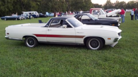2007 Ford Mustang - A white 1970 Ford Ranchero with a distinctive red and brown side stripe is parked on grass at an outdoor car show.