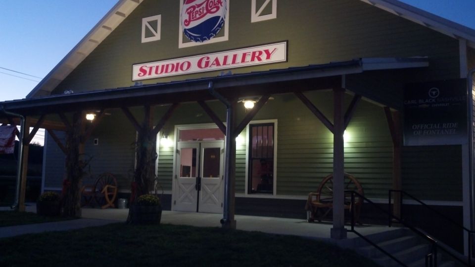 Green building with a Pepsi logo and "STUDIO GALLERY" sign, porch with lights, and decorative wagon wheels